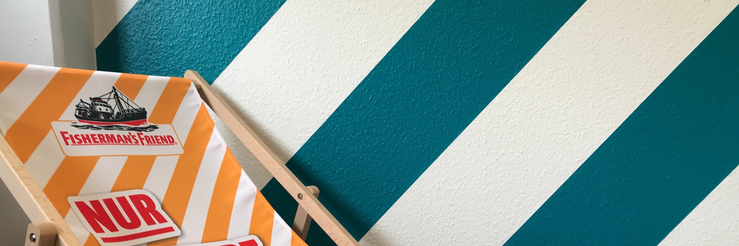 Modern gestaltete Wand mit breiten türkisen und weißen diagonalen Streifen als Beispiel für exakte Farbkanten.